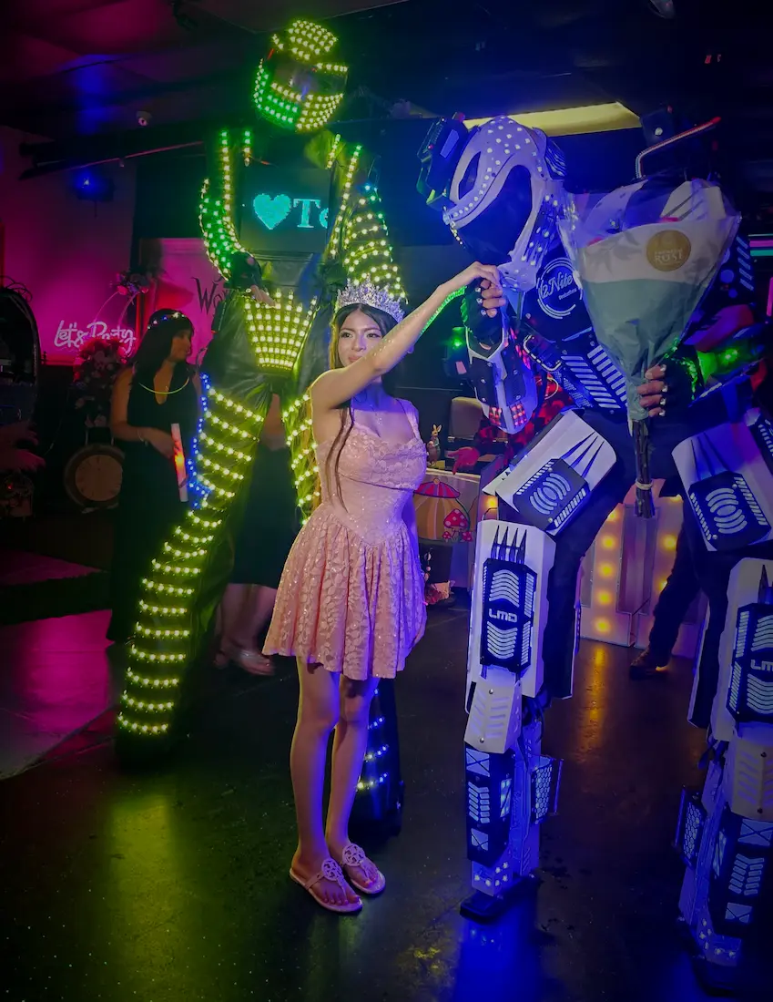 Color-changing LED stilt robot performing with guests on an LED dance floor