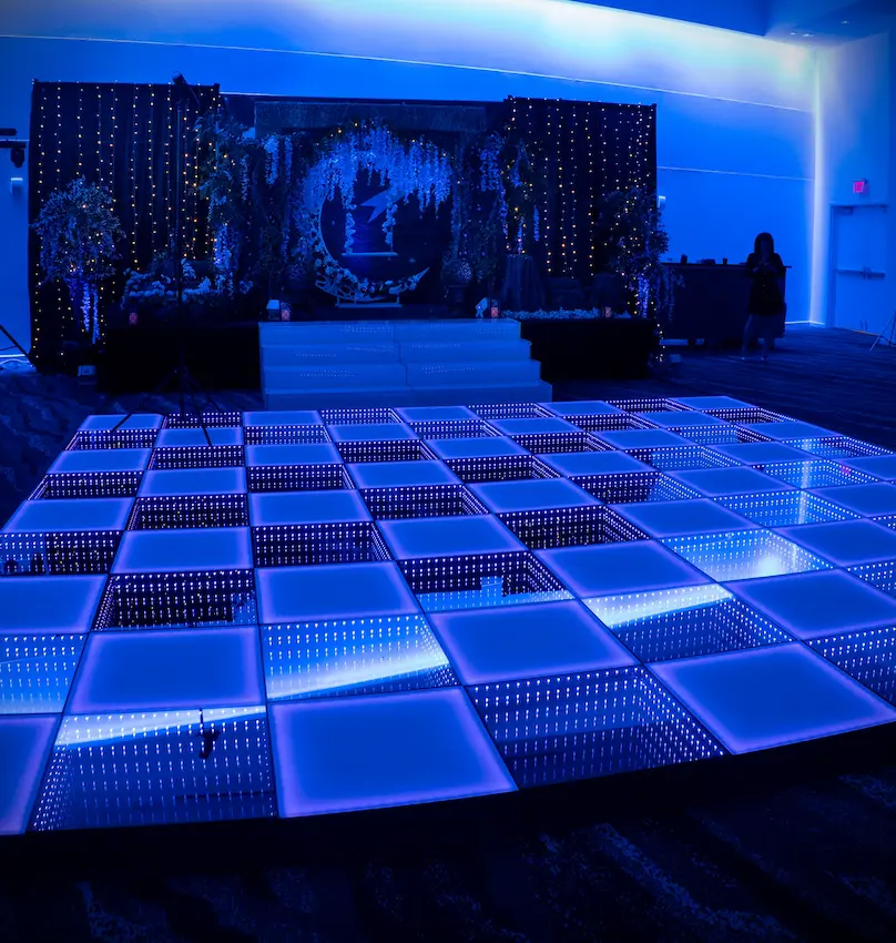 Infinity LED dance floor leading to a black-skirted stage at Illuminate Event Venue in Sunrise