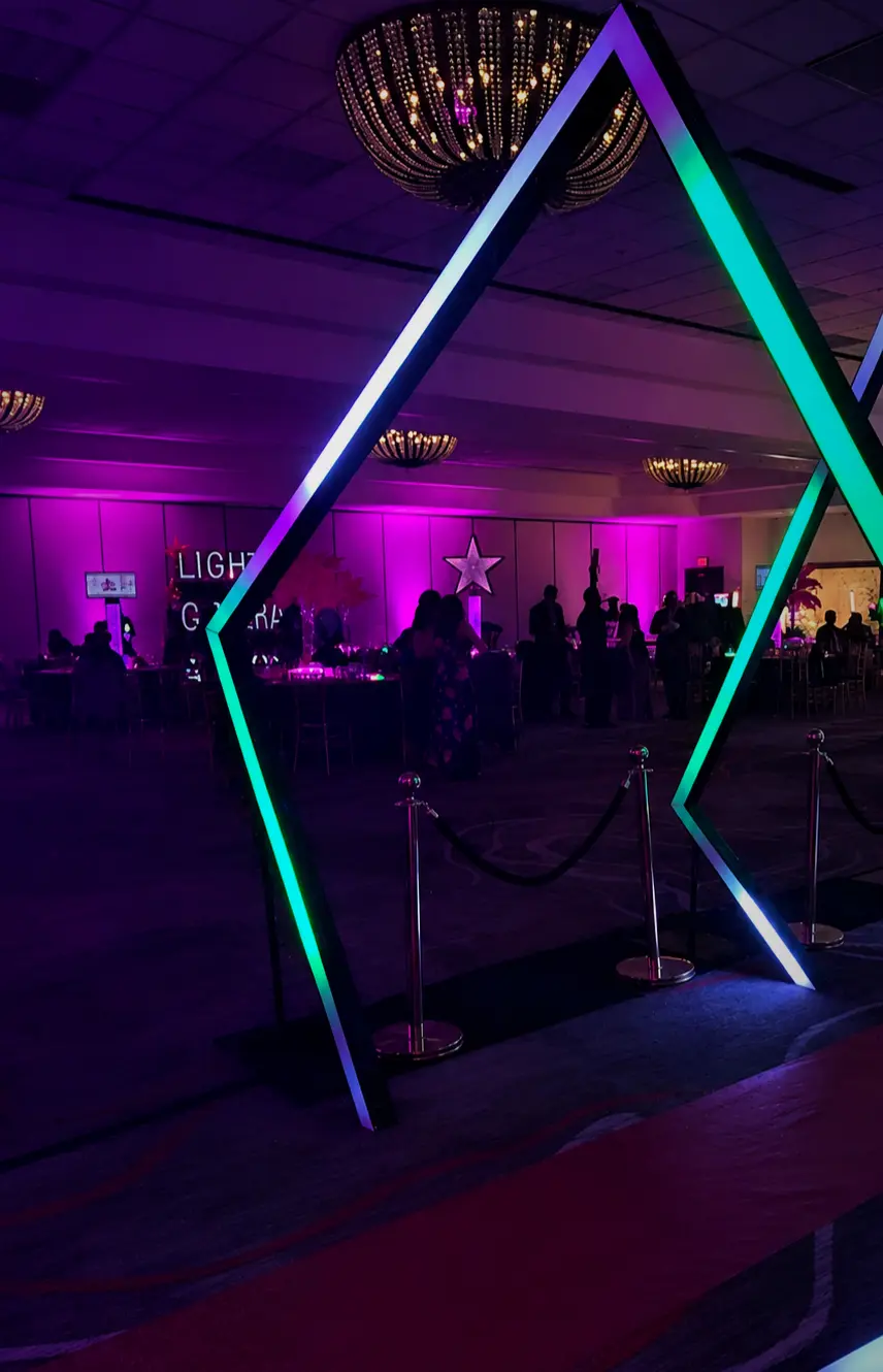 Pink ballroom uplighting behind a geometric LED entrance arch at a Coral Springs Bat Mitzvah