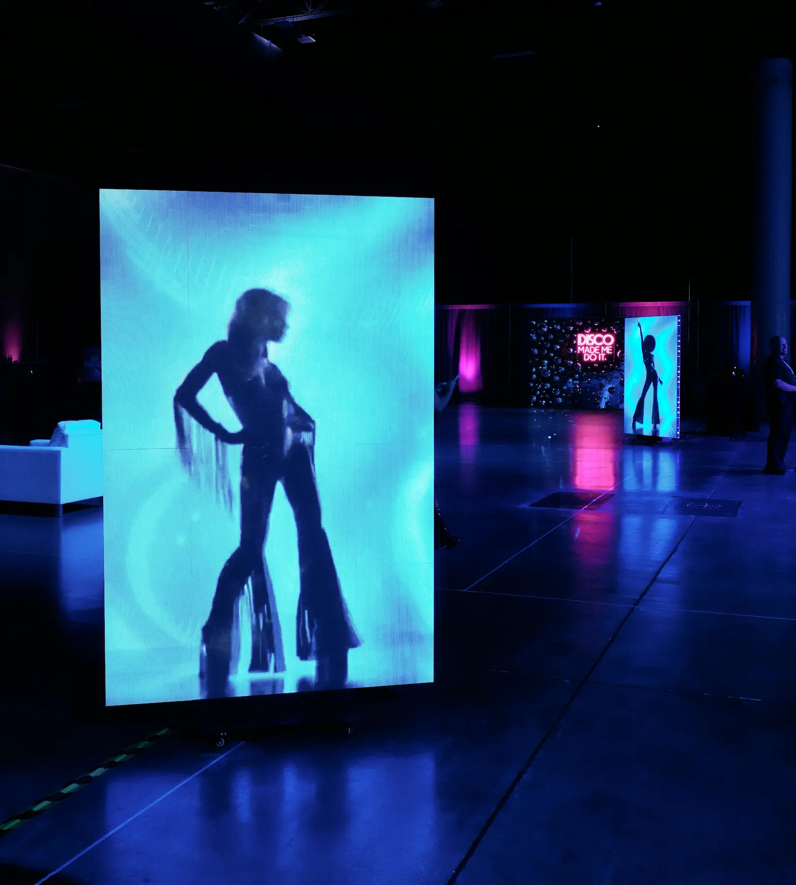 Freestanding vertical LED display showing a blue silhouette visual at the corporate party