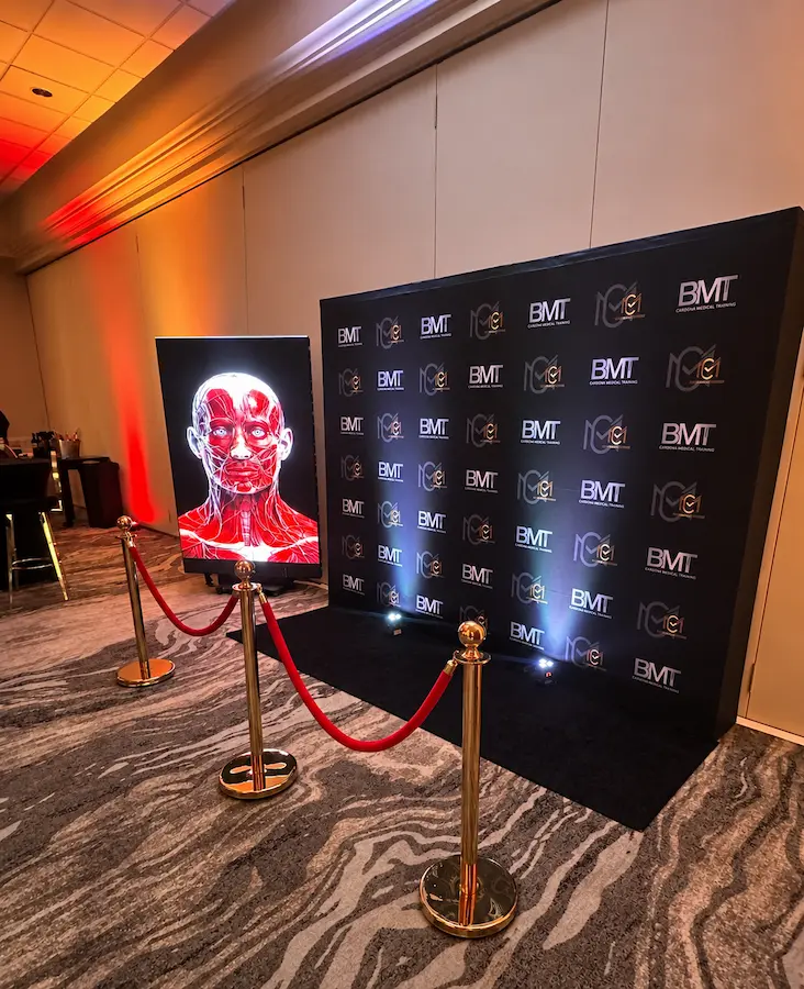 Vertical LED display with branded backdrop and amber uplighting at the Top Injector book launch in Miami