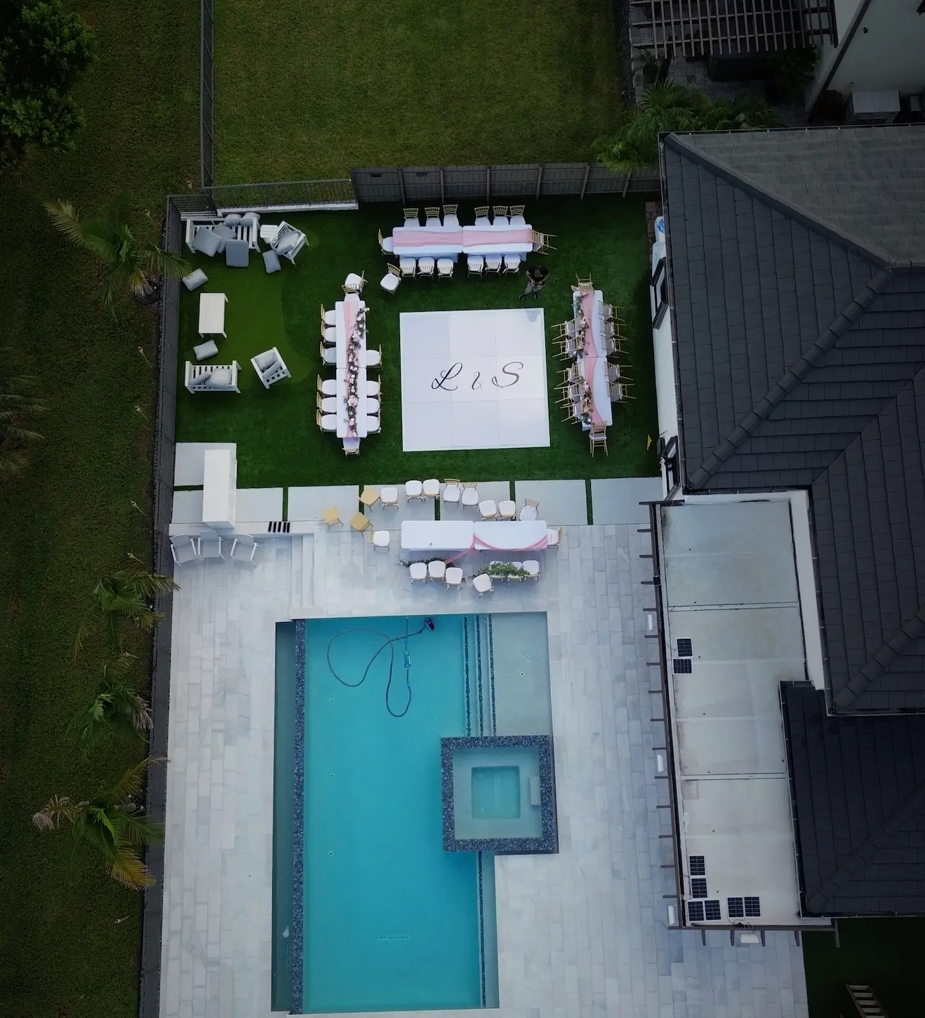 Drone view of a Miami backyard wedding with a custom white dance floor on artificial grass near the pool