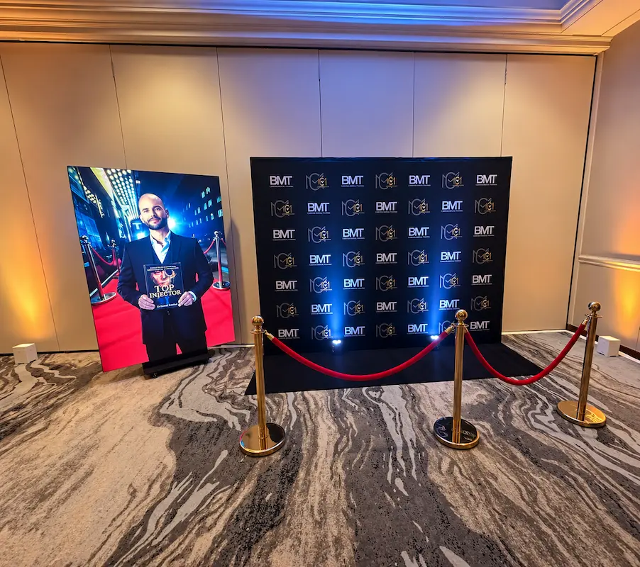 Vertical LED screen beside a branded entrance backdrop with corporate uplighting at the Top Injector book launch in Miami