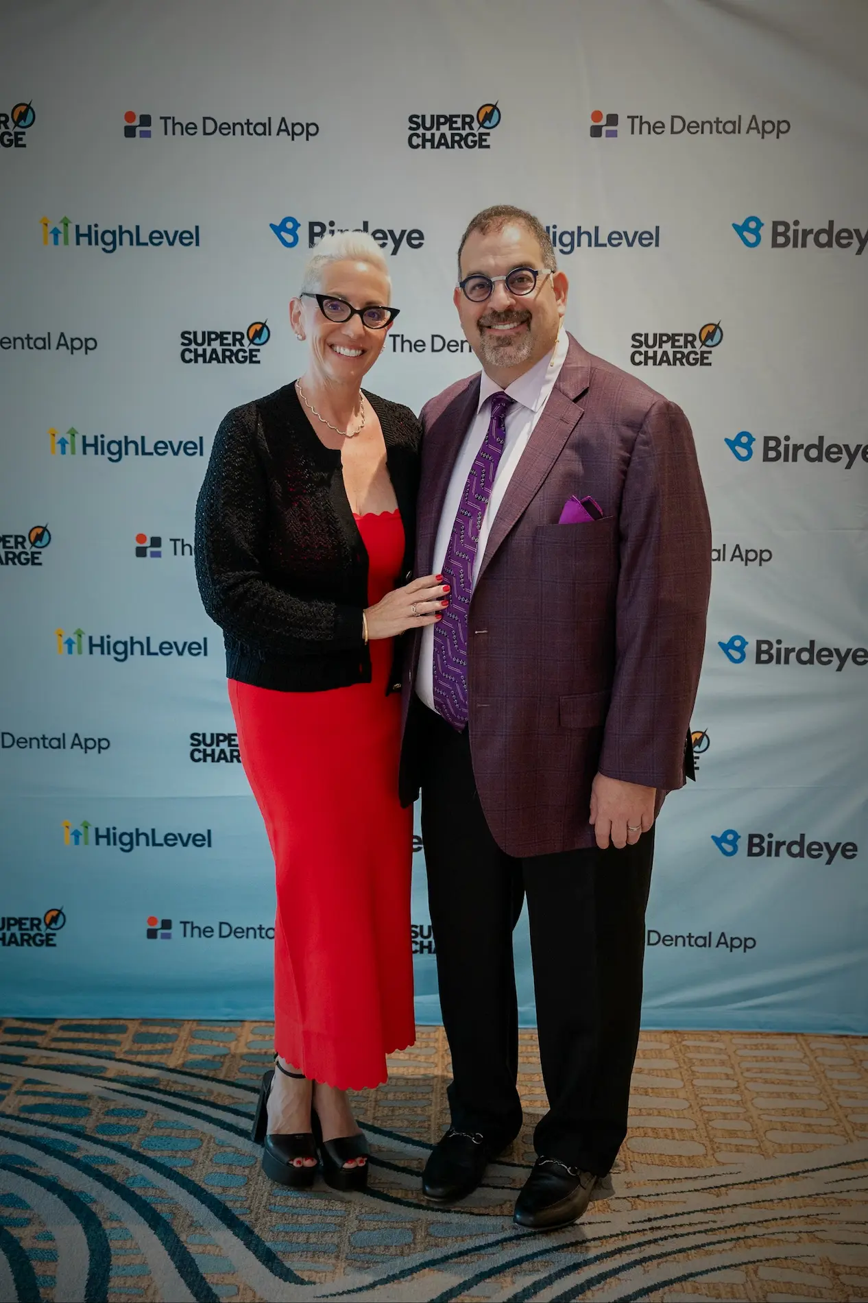 Dr. Len Tau with a guest at the Supercharge conference backdrop