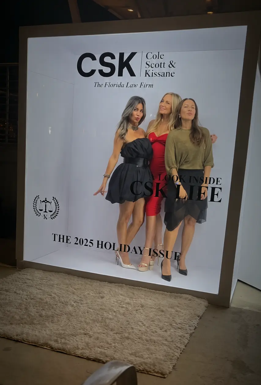 Three guests posing inside the branded magazine booth at CSK’s holiday celebration in Miami